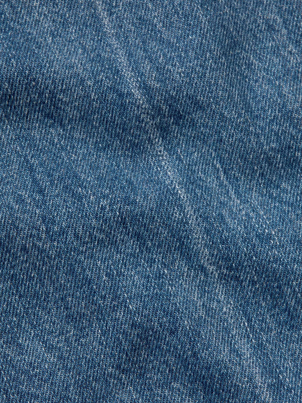 Medium-wash denim fabric close-up showing blue textured weave.