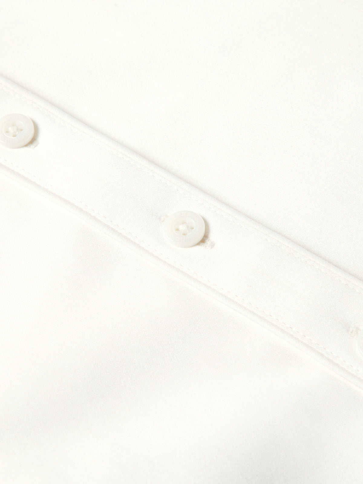 Close-up of white shirt button placket with round white buttons and stitched seams