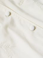Cream blouse front with decorative embroidery and fabric-covered button closures