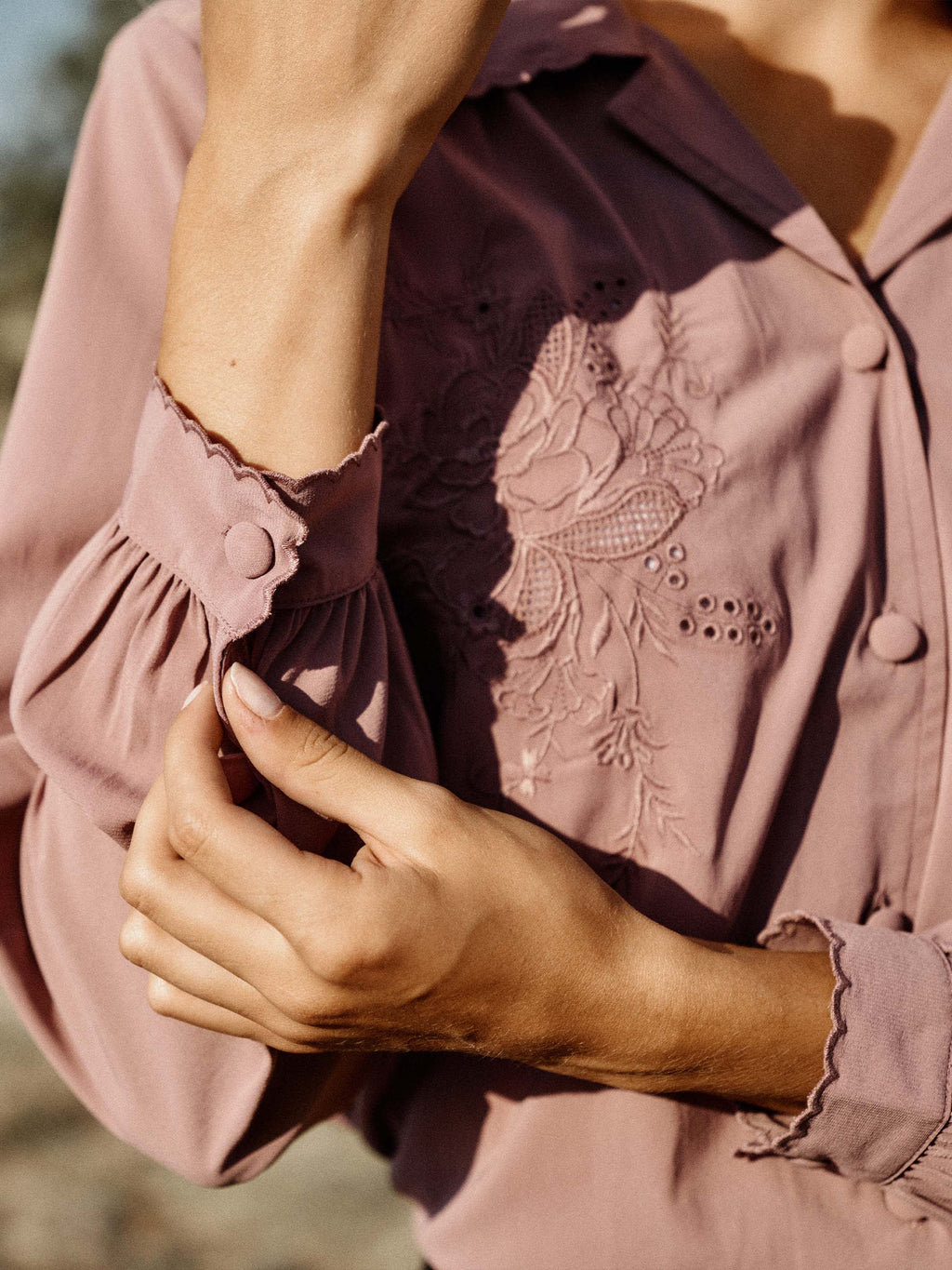 Close-up of washed plum blouse sleeve and embroidered yoke with scalloped ruffle trim