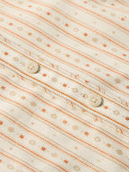 Women's printed button-up shirt fabric detail with orange striped and floral motifs