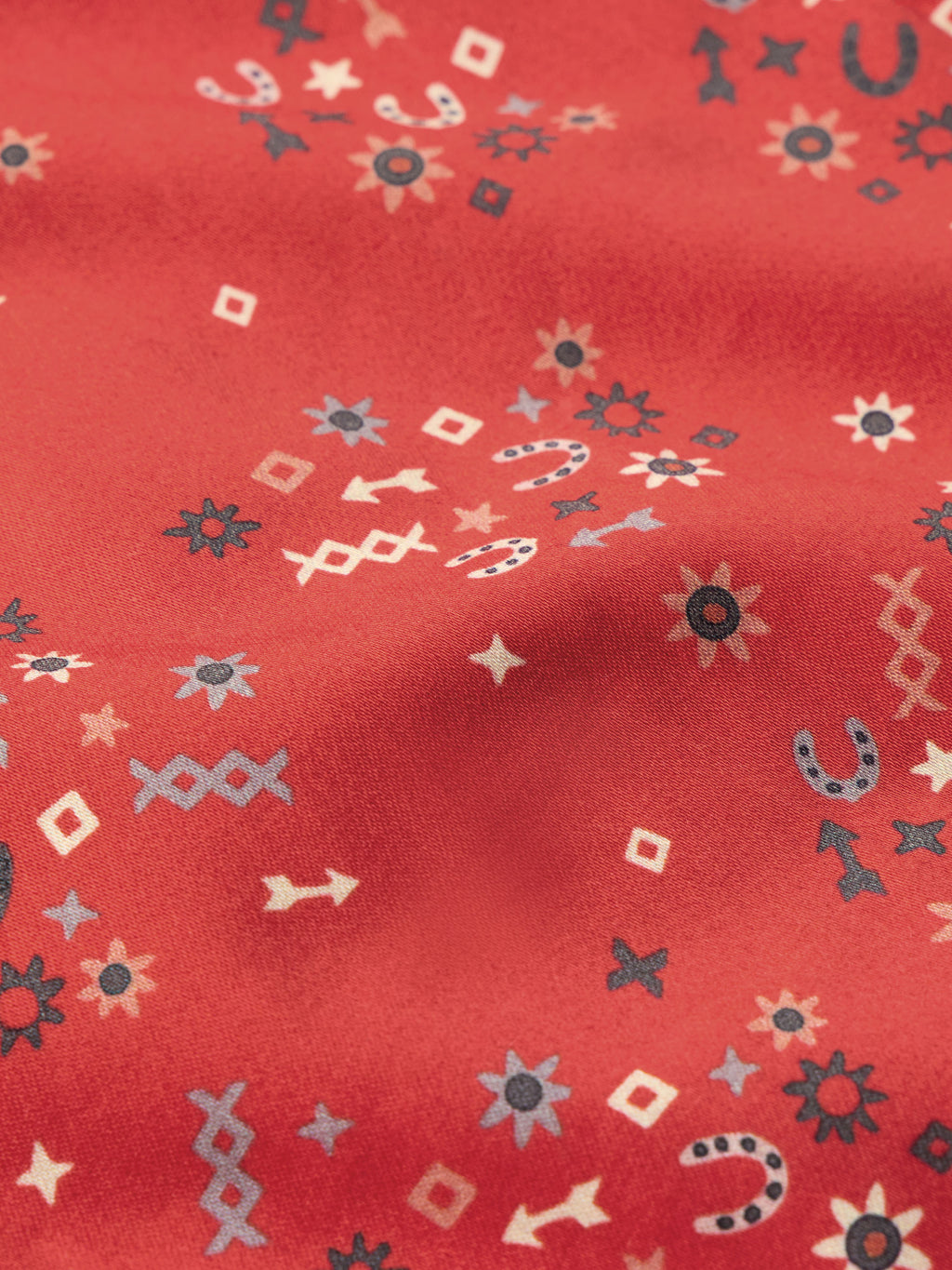 Red printed reata shirt fabric close-up with small icons pattern