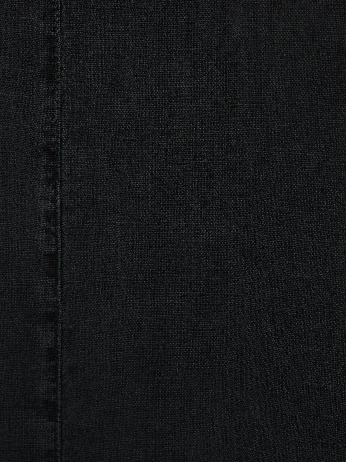 Washed black textured denim fabric with visible vertical seam