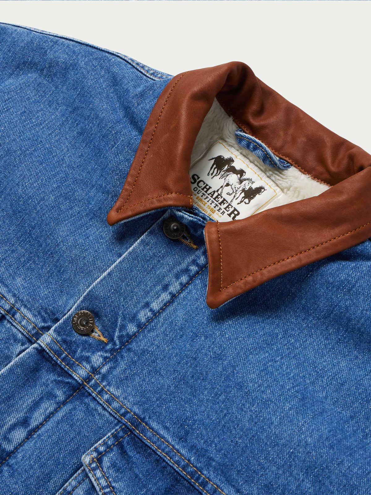 Denim jacket with brown buttoned collar and visible fleece lining at neckline