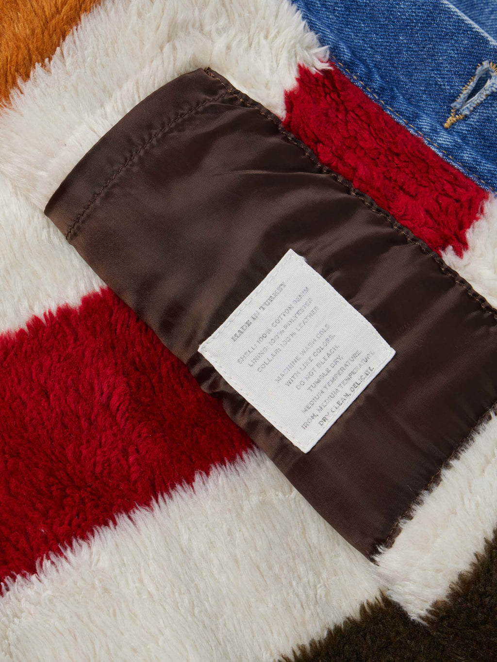Striped fleece lining inside denim jacket with brown fabric binding and label