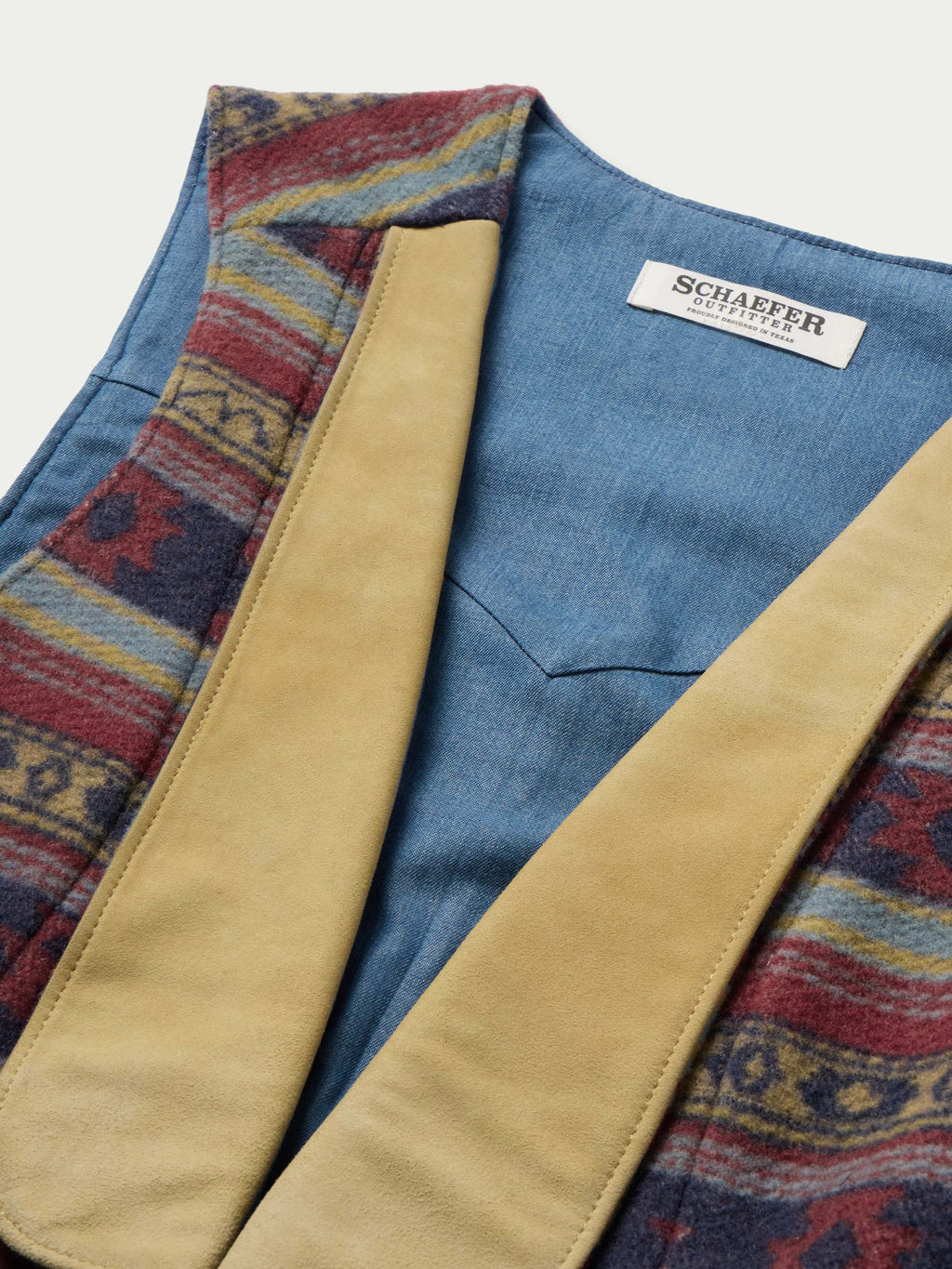 Women's wool vest detail: tan trim, blue lining, multicolor woven border, brand label
