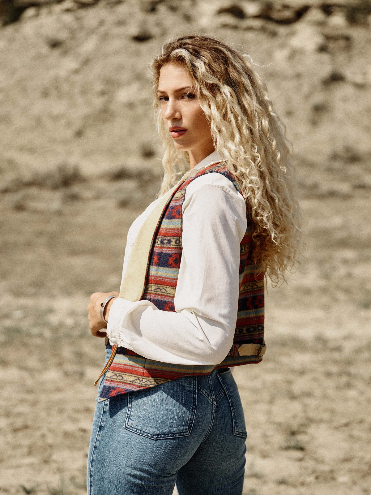 Women's patterned wool vest over white blouse; side view shows tan V-back trim