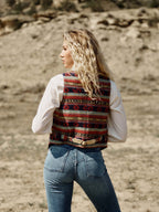 Women's patterned wool vest worn over white sleeves; V-back with tan trim