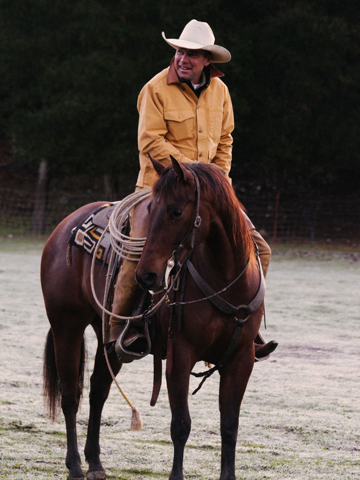 Suntan brush jacket on a cowboy next to a saddle horse