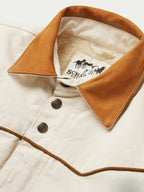 Natural drifter coat collar close-up with tan lining, snap buttons, and brand label inside.