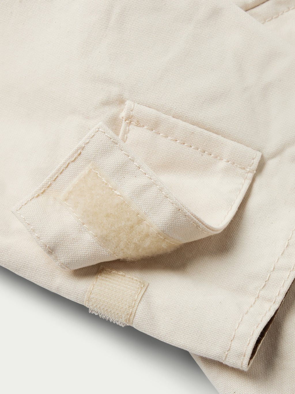 Natural drifter coat cuff close-up with stitched hem and textured wear at the end.