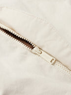 Natural canvas coat zipper detail with white stitching and snap placket
