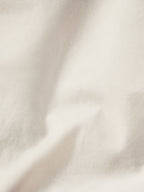 Natural canvas coat fabric close-up with light texture and neat seams