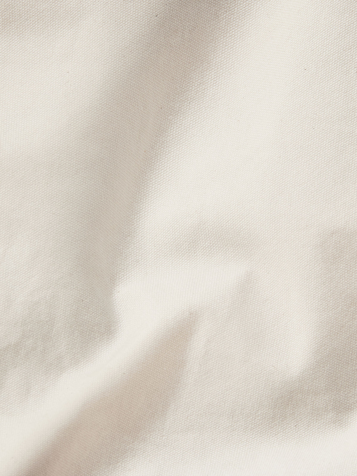 Natural canvas coat fabric close-up with light texture and neat seams