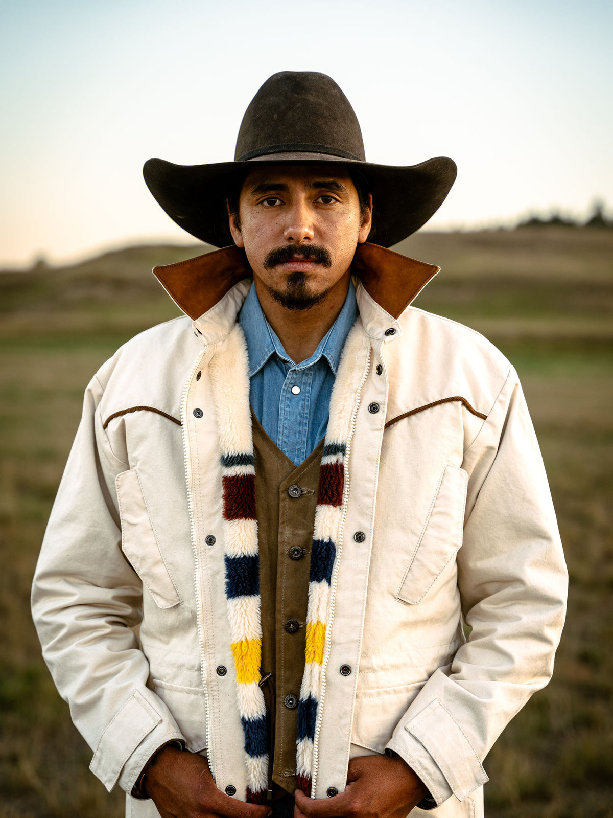 Natural drifter coat on man with brown cowboy hat, multicolor striped sherpa yoke