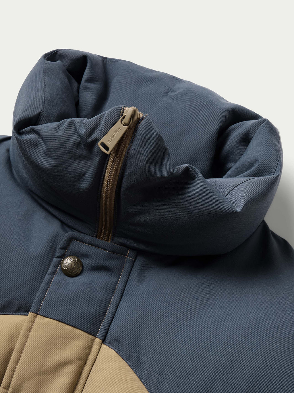 Dark navy puffer jacket corner detail with zipper and snap placket