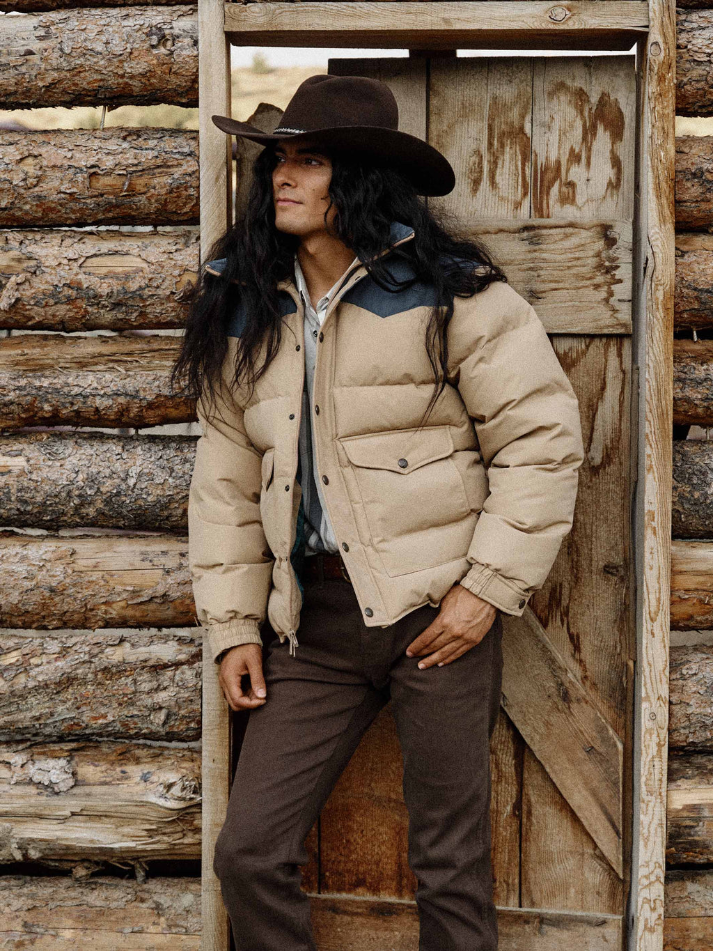 Man wearing camel and dark navy down jacket standing outdoors