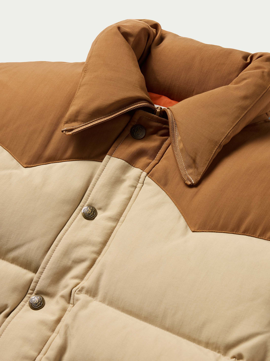 Tan and cream down jacket close-up: stand collar, zip placket, snap details