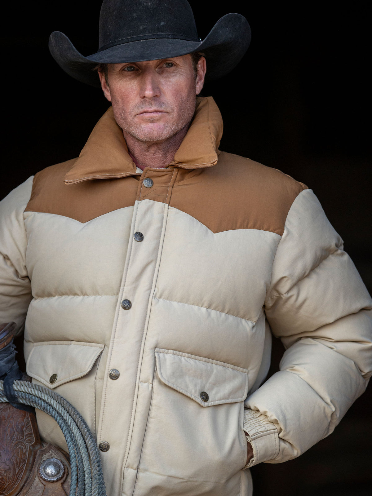 Tan and cream color-block down jacket close-up with snap button placket and pockets