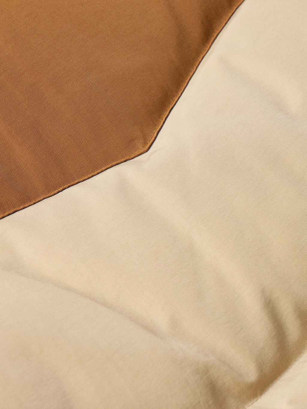 Tan down jacket with two-tone fabric panel and stitched seam