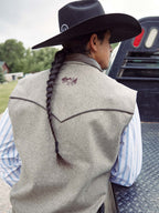 Taupe wool vest worn with braided tie detail on back and embroidered logo