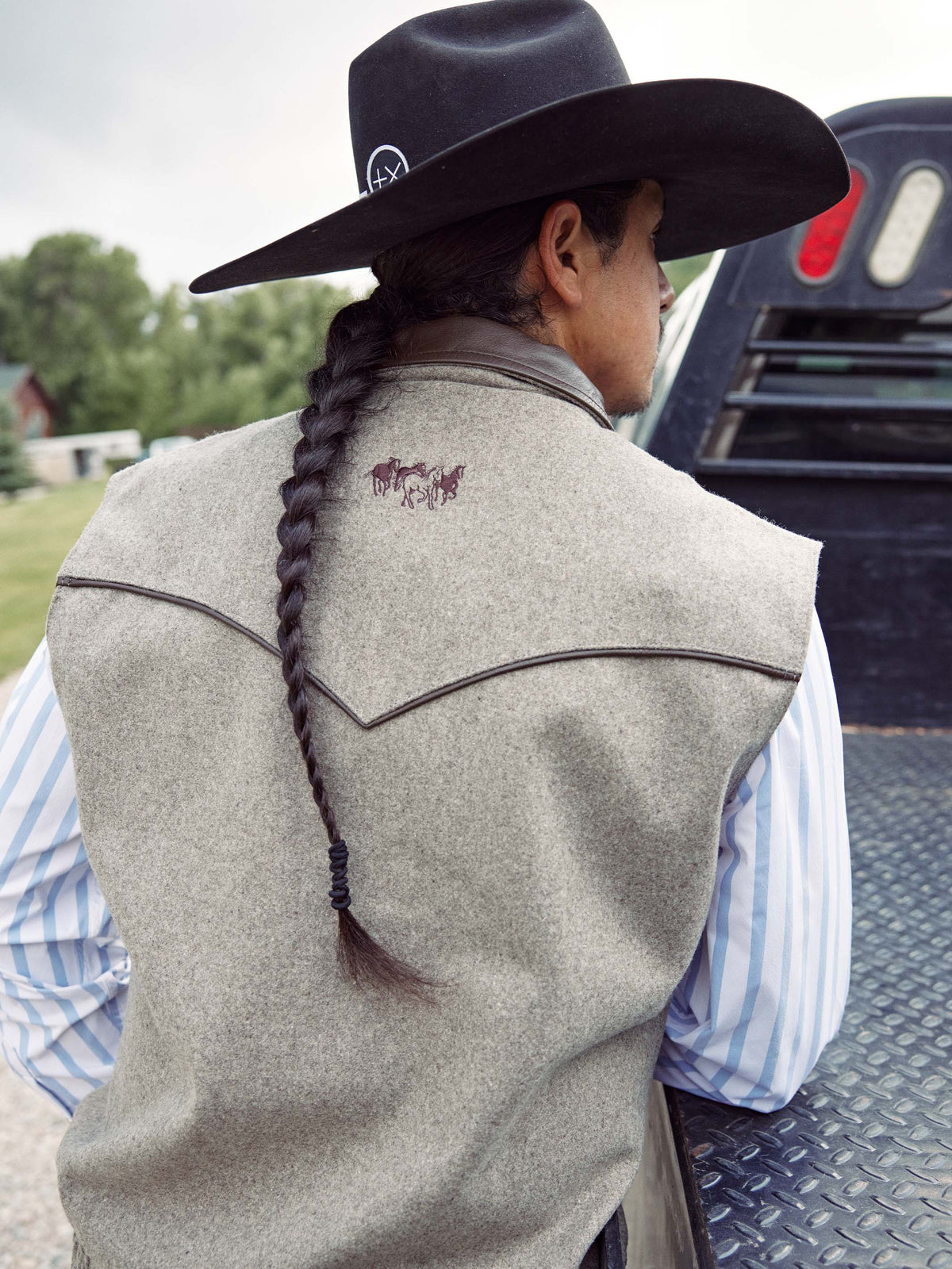 Taupe wool vest worn with braided tie detail on back and embroidered logo