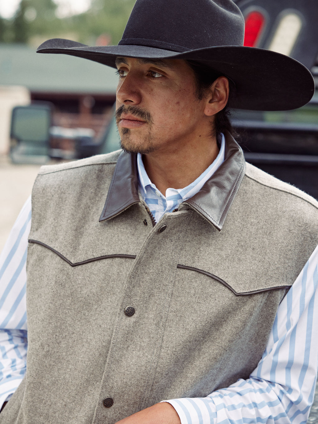 Taupe wool vest close-up with stand collar, button front, and dark leather trim
