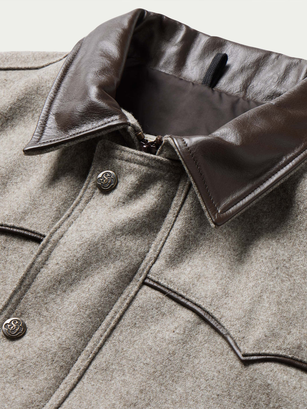 Taupe wool vest close-up with dark leather-trimmed collar and snap-button front