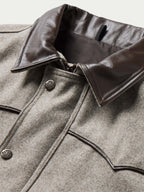 Taupe wool vest close-up with dark leather-trimmed collar and snap-button front