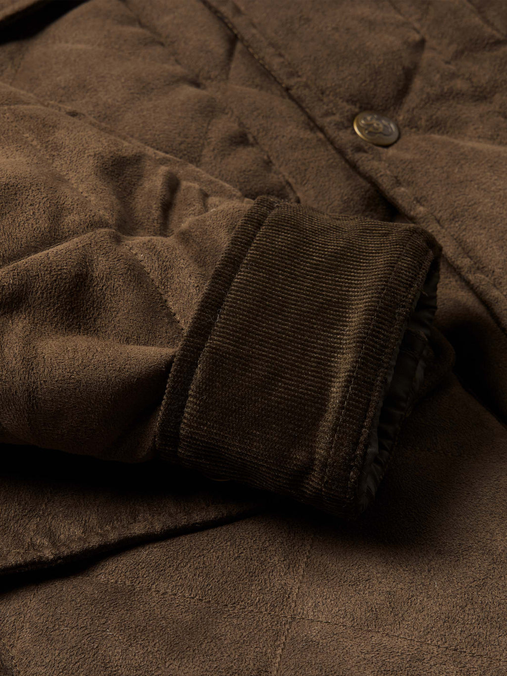 Brown quilted microsuede jacket sleeve cuff with knit trim and snap button.