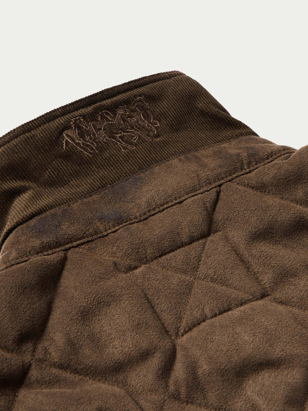 Brown quilted microsuede jacket interior collar lining with embroidered logo patch.