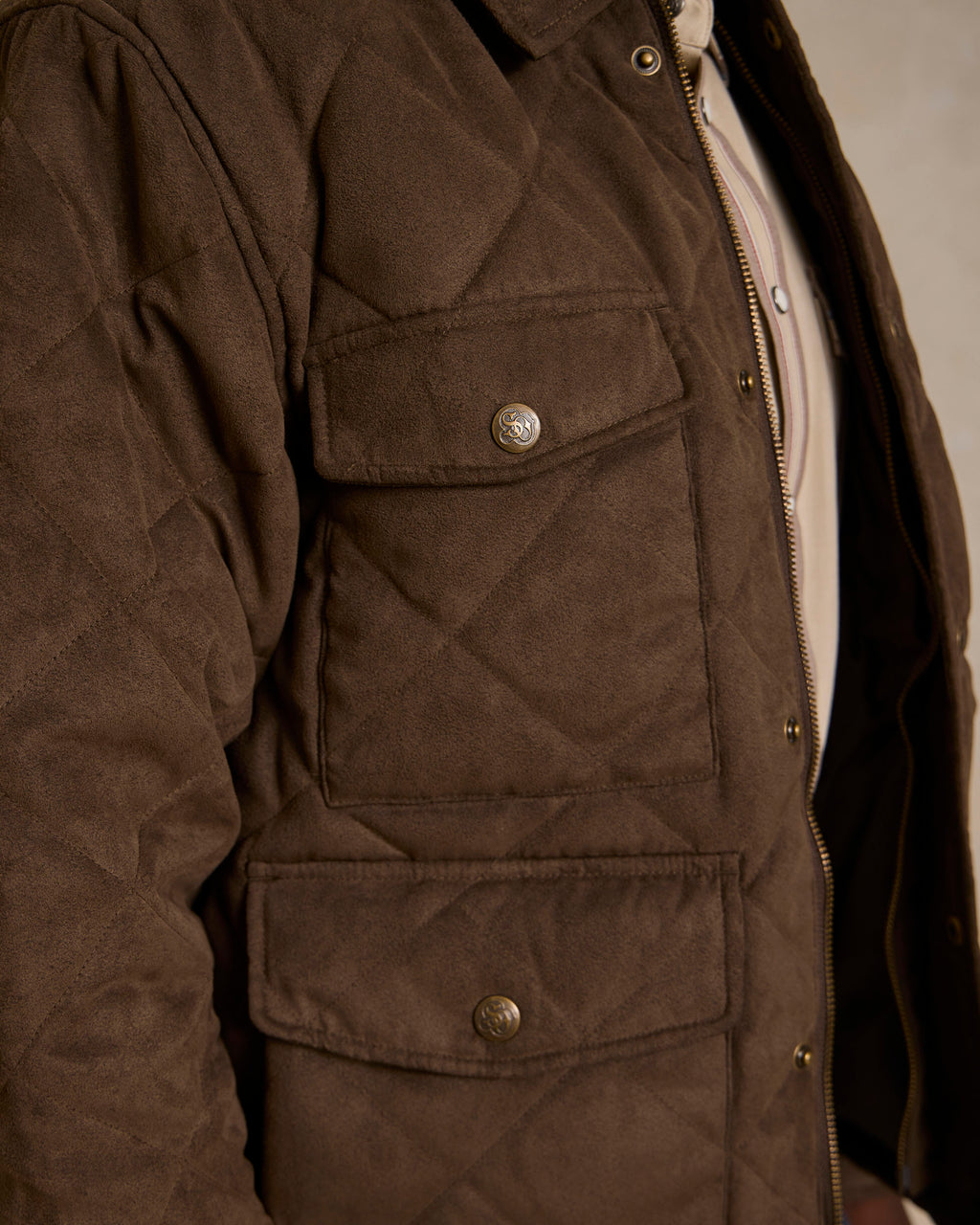 Brown quilted microsuede jacket detail: snap flap pockets and front zipper