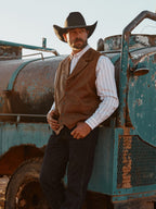 Brown leather cowboy vest with button-front, worn with cowboy hat outdoors