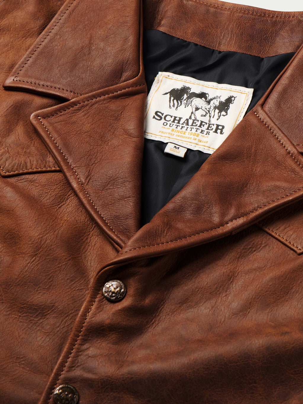 Brown leather vest with interior logo label and button placket close-up