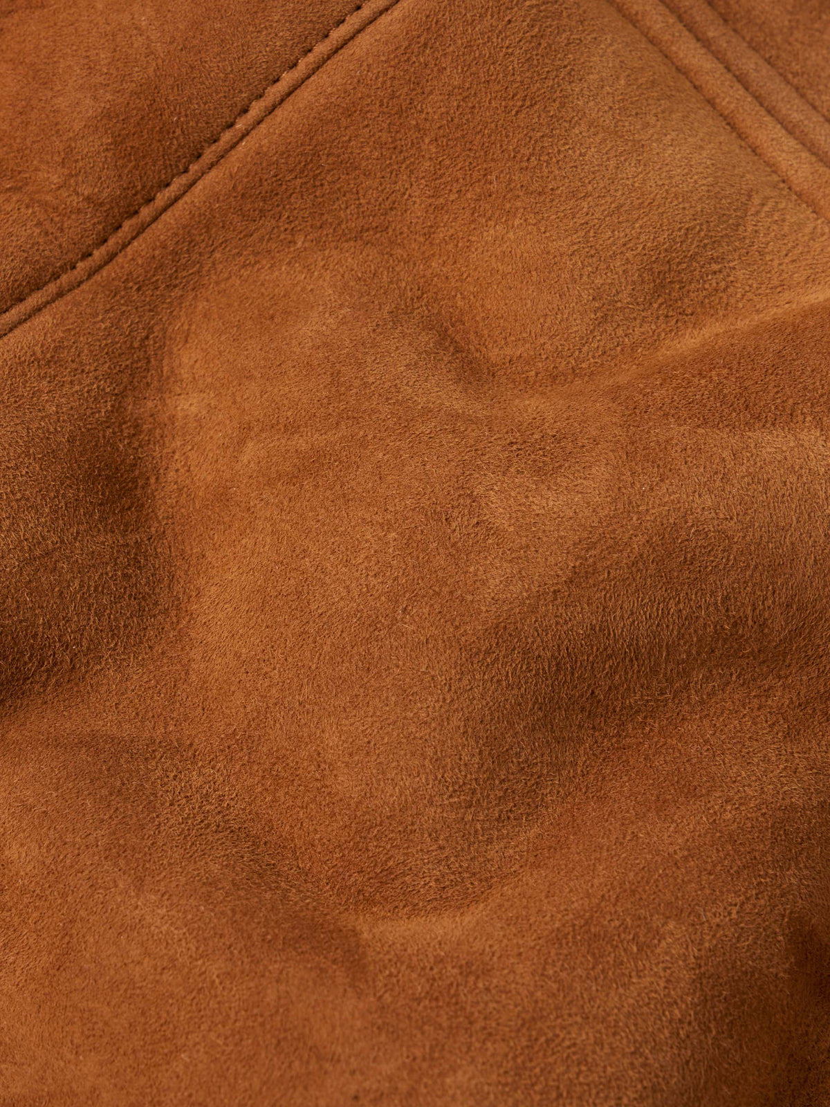 Close-up of buckskin suede fabric with stitched seams and soft nap texture