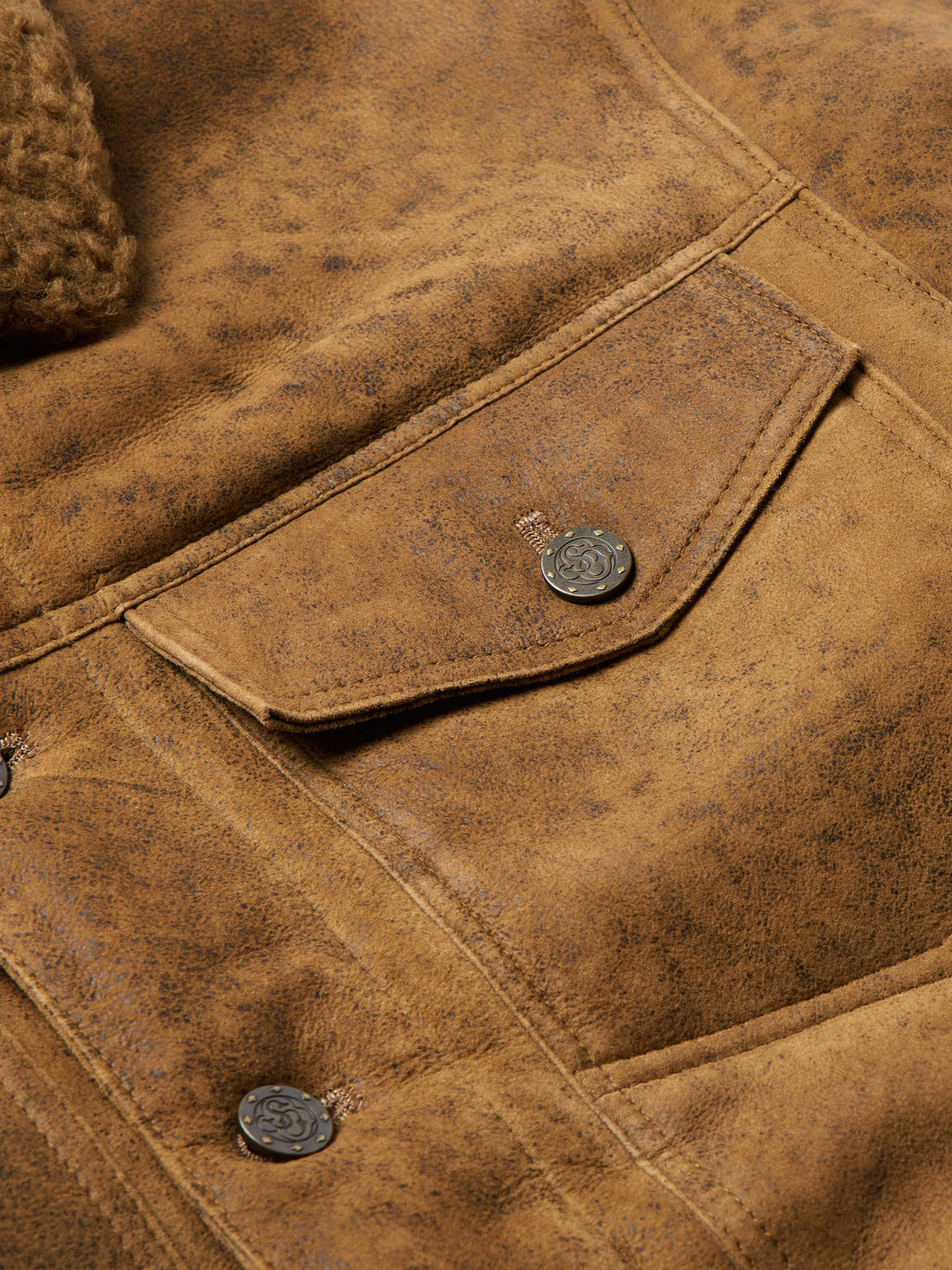 Brown trucker jacket close-up of pocket seams and round metal snap buttons