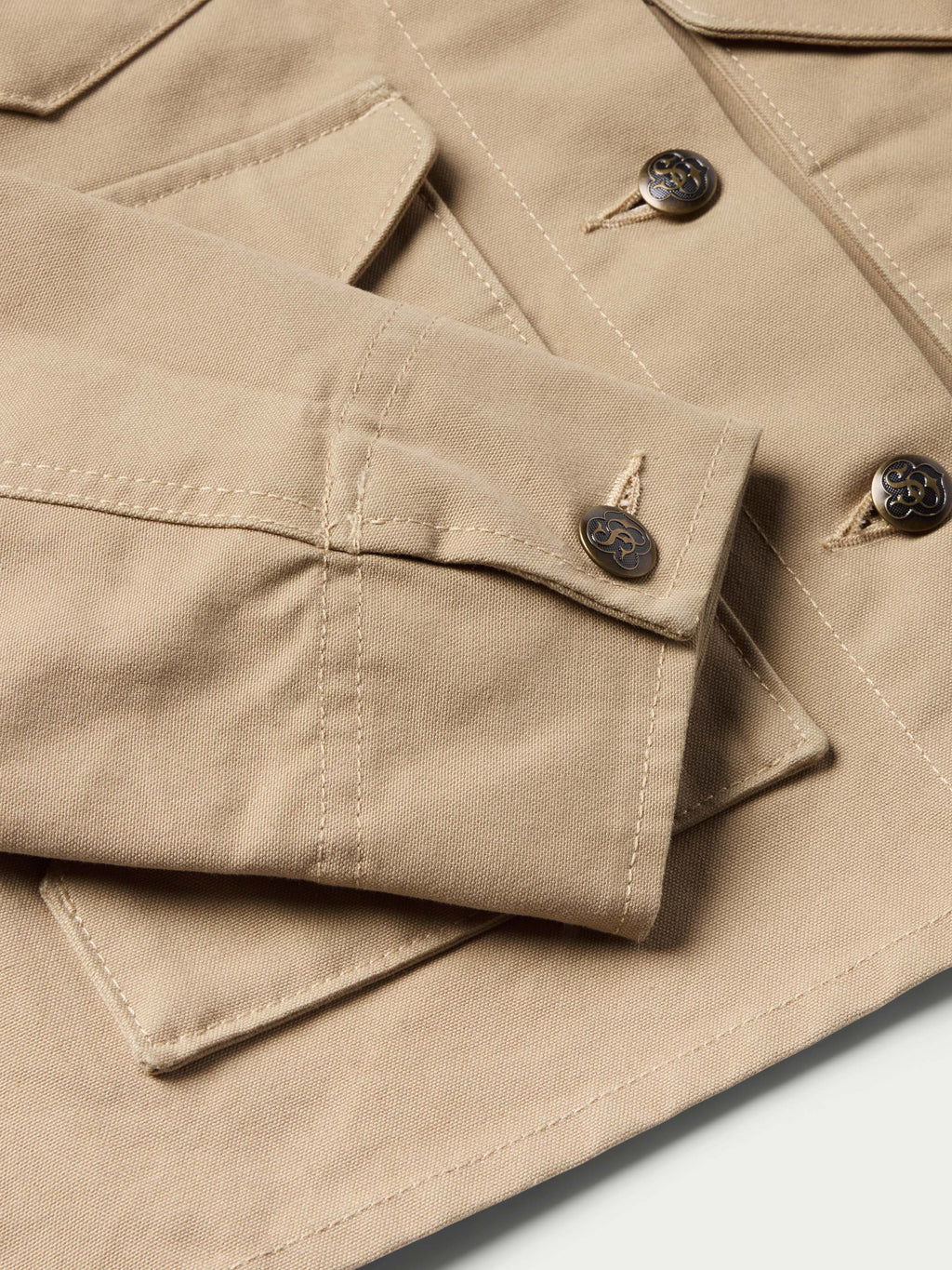 Beige jacket interior pocket flap with stitched seams and snap closures