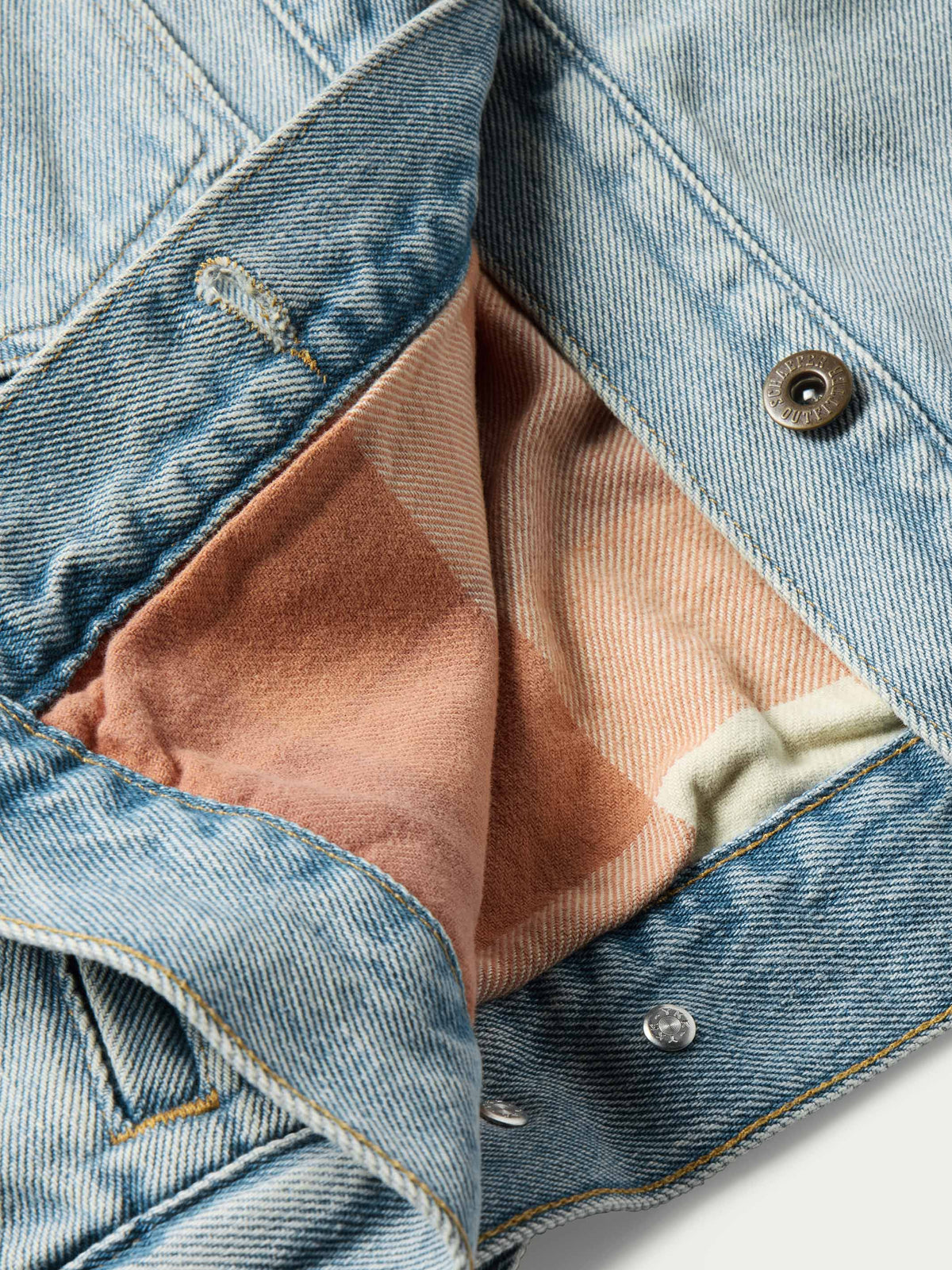 Denim jacket detail with brown flannel lining and snap buttons