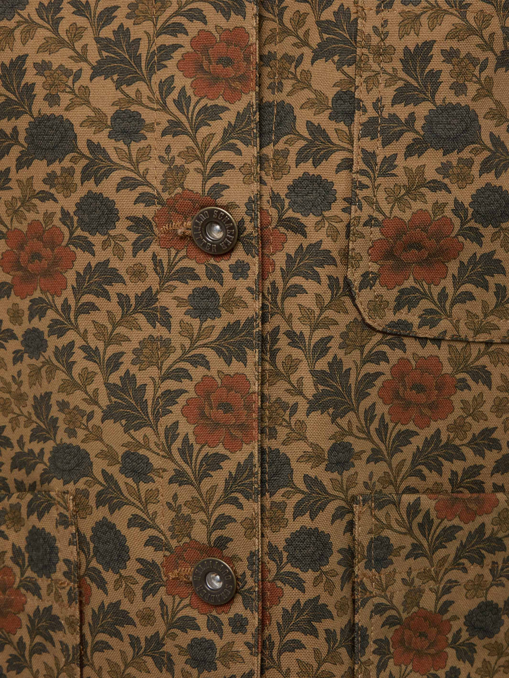 Chore coat fabric detail with floral pattern and two metal snap buttons