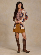 Women's belted sweater worn, cream knit with orange, navy, and brown geometric pattern.