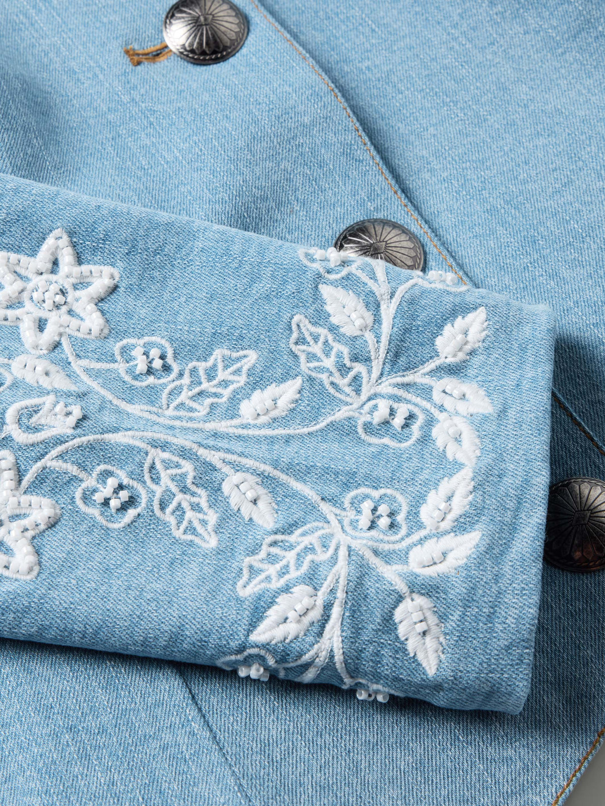 Light wash denim sleeve with white floral and star bead-embroidered design