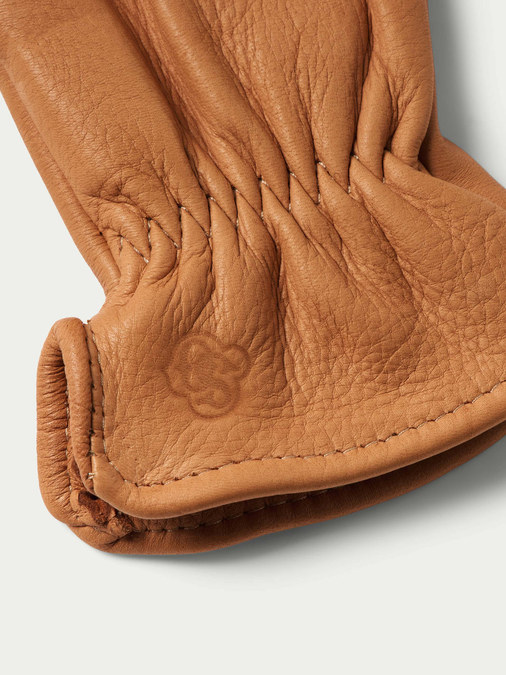 Deerskin glove palm closeup with stitched finger seams and embossed logo