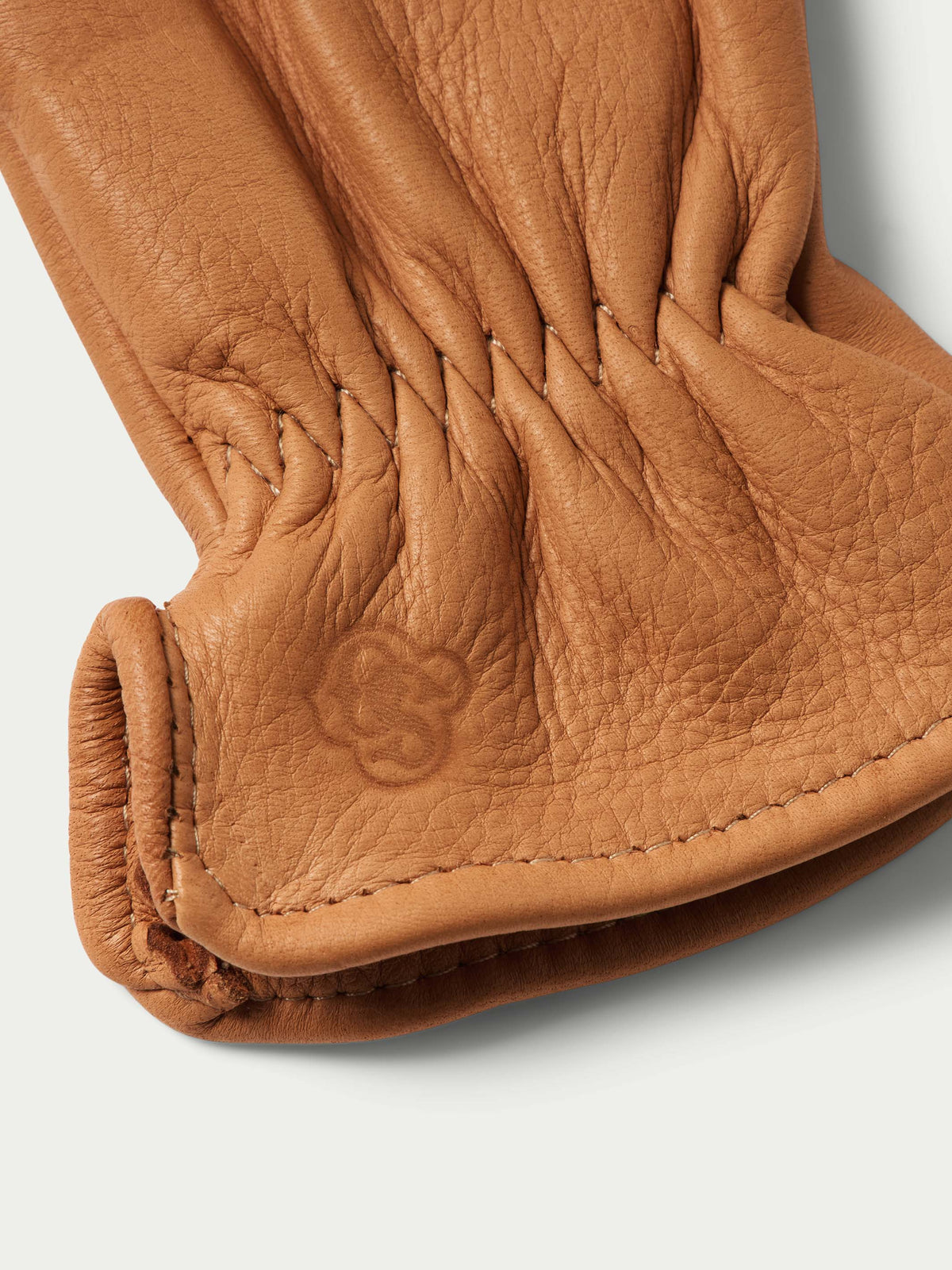 Deerskin glove palm closeup with stitched finger seams and embossed logo