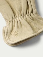 Natural goatskin glove cuff with embossed clover-like logo and stitched edge