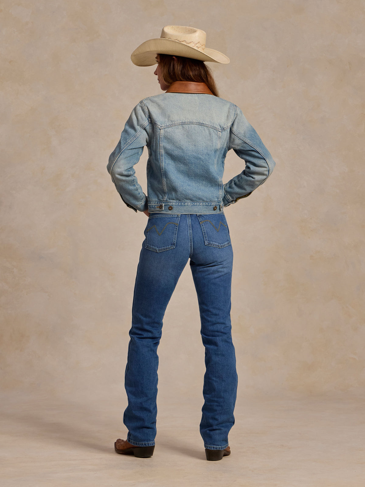 Back view of light blue denim jacket with brown flannel collar and snap details