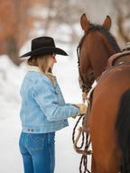 Sherpa-lined light wash denim jacket worn while standing beside a horse