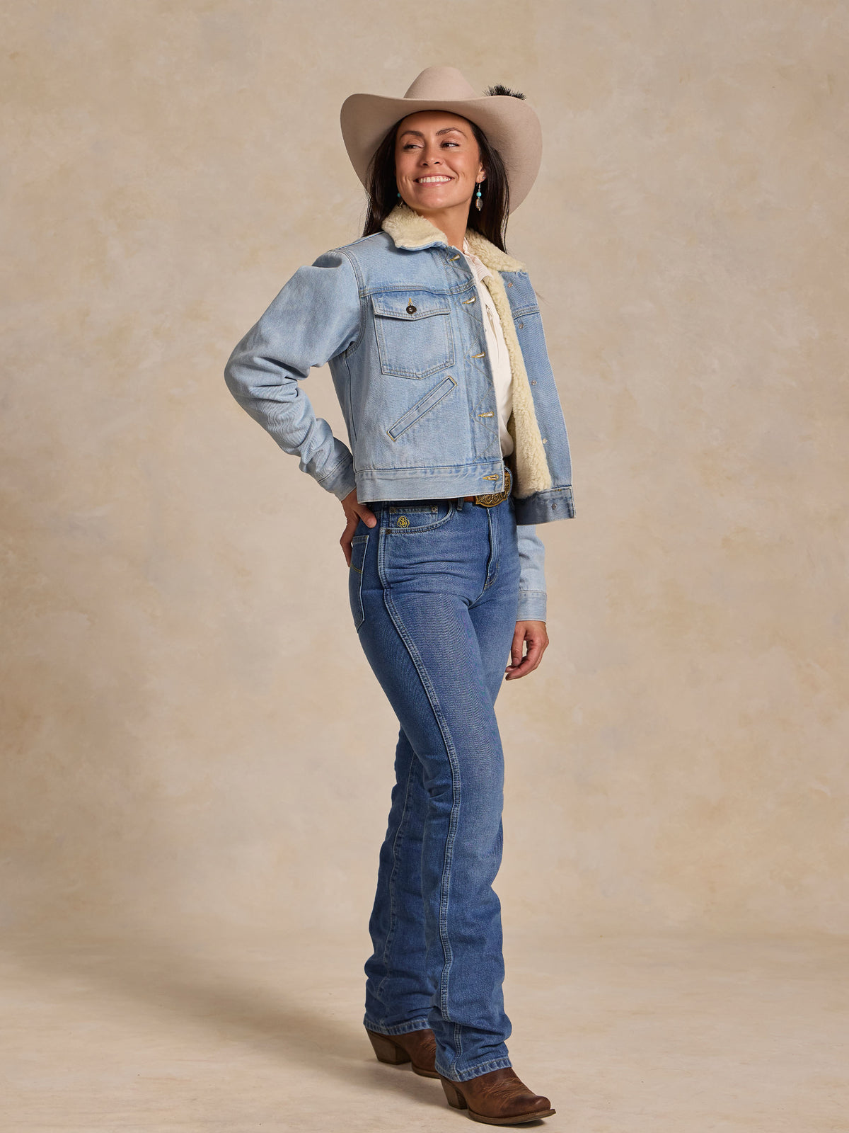 Sherpa-lined light wash denim jacket worn by a model with a tan hat