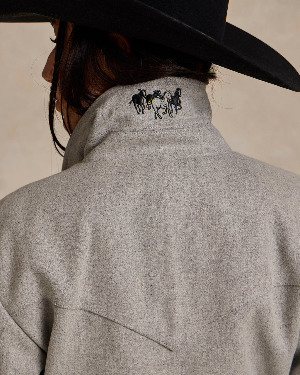 Light gray wool rancher jacket back panel with horse logo and curved seam