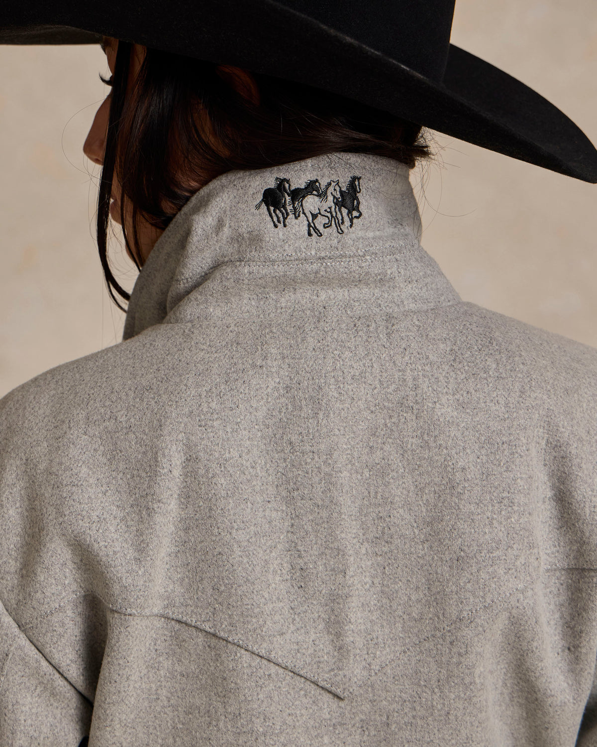 Light gray wool rancher jacket back panel with horse logo and curved seam