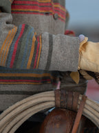 Striped jacket sleeve detail with tan leather-look cuff and metal snap hardware